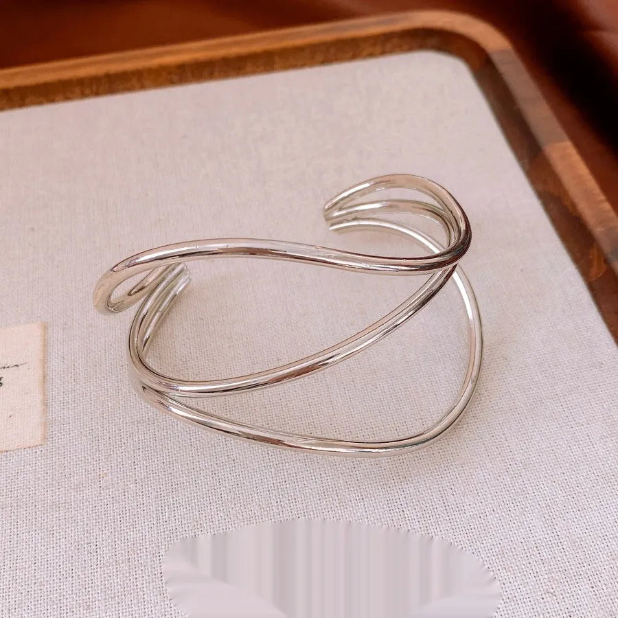Open-ended metal bracelet with geometric irregular lines, round element, available in gold or silver