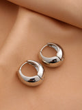 Smooth geometric hollow earrings for women in golden finish, set on a dark background