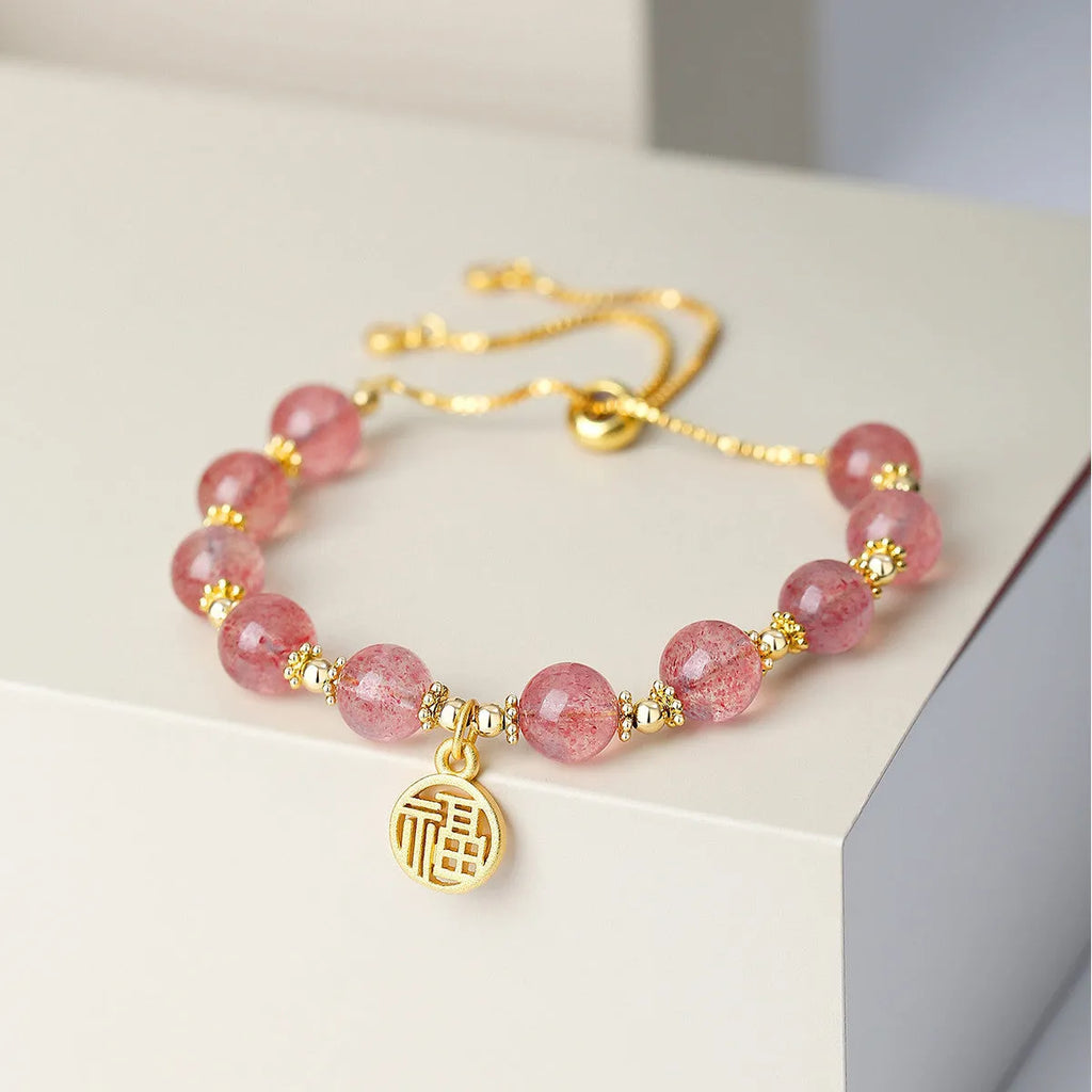 Women's strawberry quartz bracelet with a geometric fu character charm on an electroplated chain.