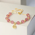 Women's strawberry quartz bracelet with a geometric fu character charm on an electroplated chain.