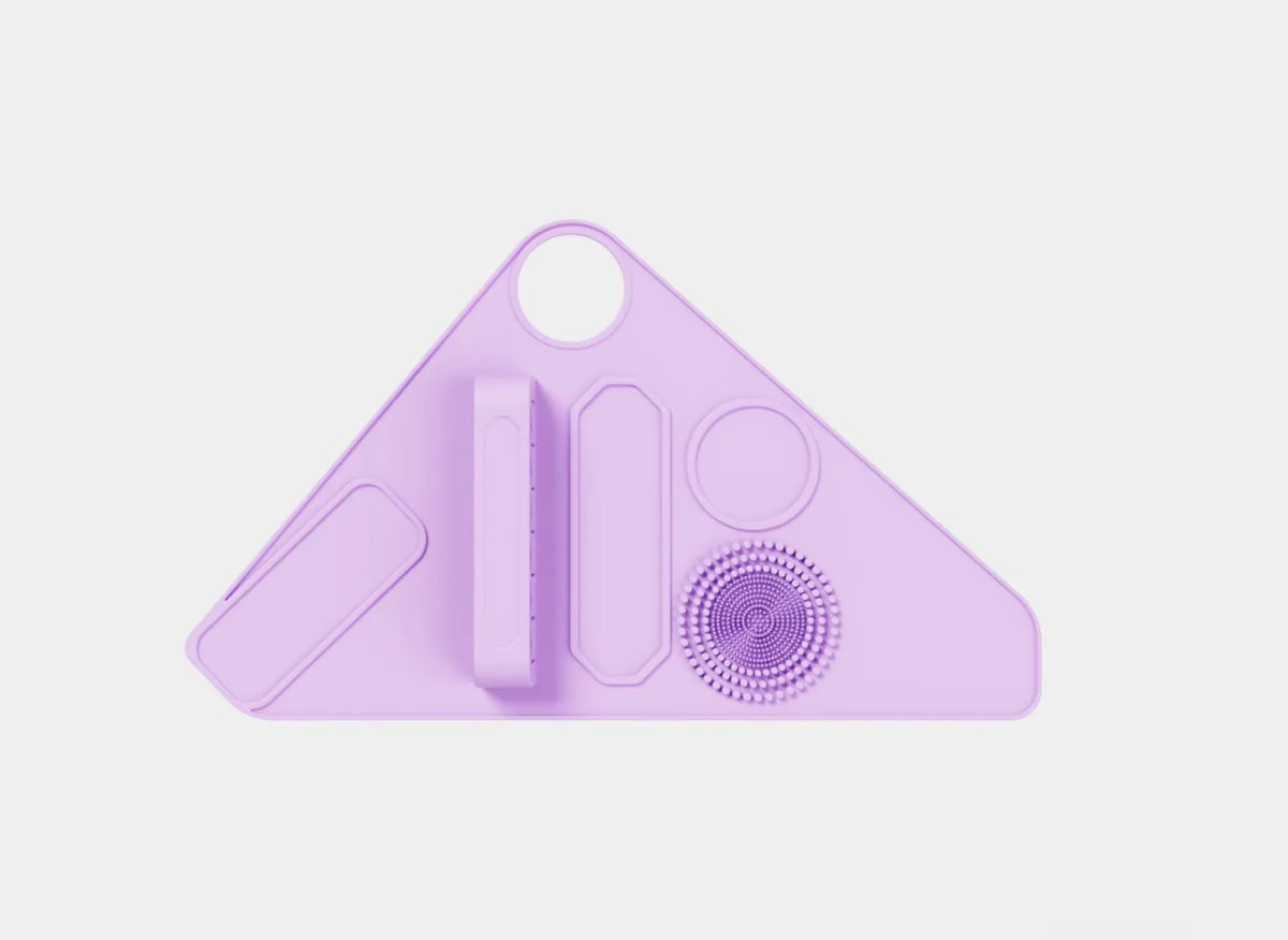Silicone makeup auxiliary hand strap in four colours: purple, pink, blue, and black, on a light background showing regular size and flexible material.