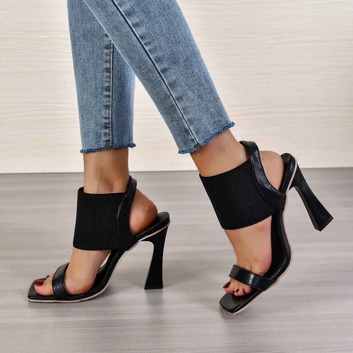 Women's black high heel sandals with an elastic strap across the foot and a rubber sole.