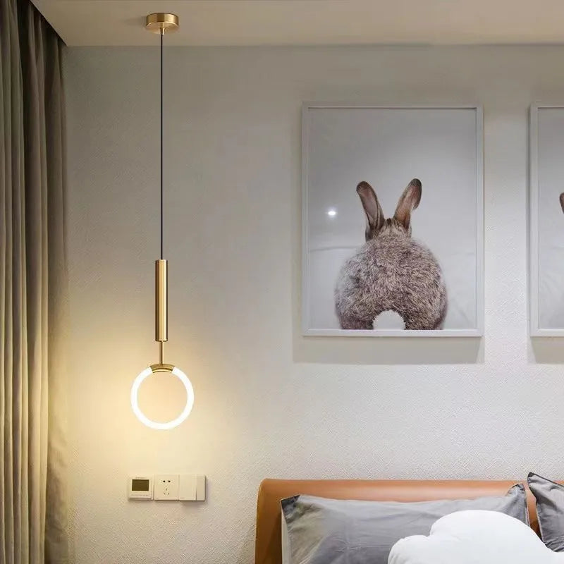 Minimalist black U-shaped pendant light with a downward-facing bulb mounted next to a bed.