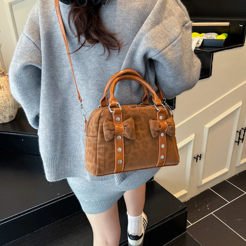 Soft PU pillow bag with crossbody strap, stitching, rivets, and leopard print in brown with pendant