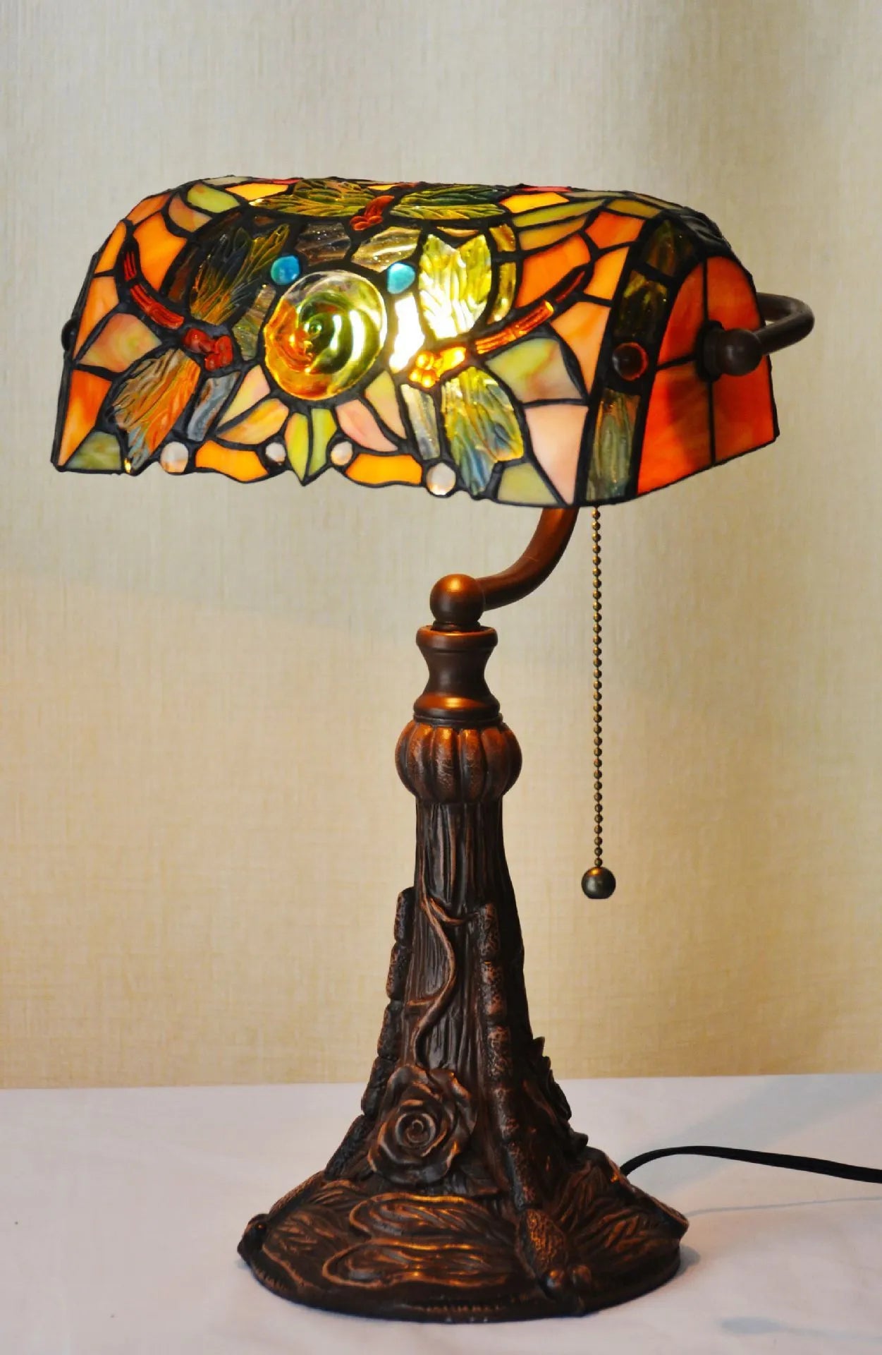 Tiffany-style desk lamp with a coloured stained glass shade on a resin base.