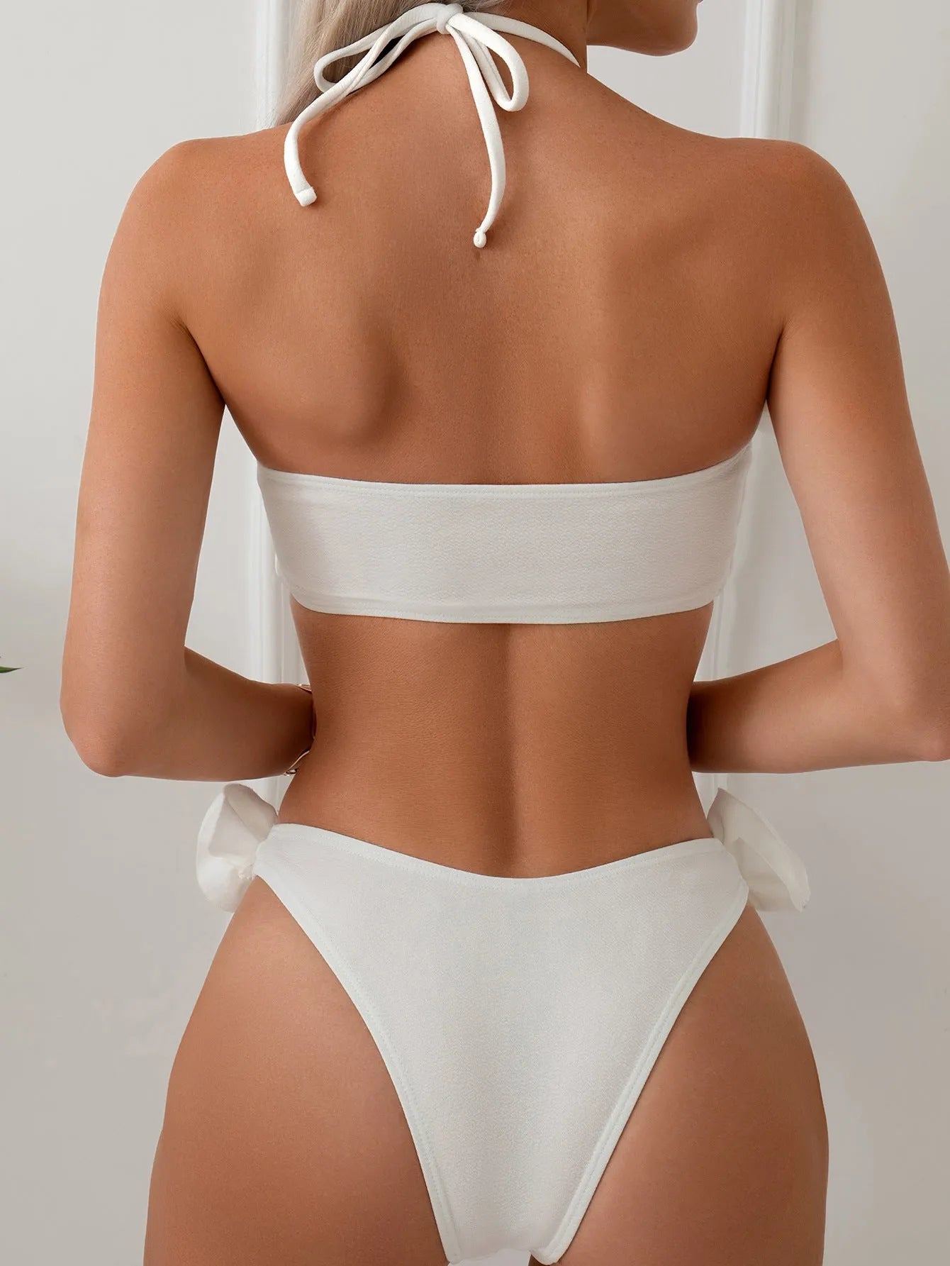 White halter neck bikini set with lace-up back and three-dimensional floral pattern on briefs.