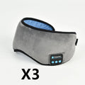 Soft satin sleep eye mask in black with adjustable strap lying flat on a light background