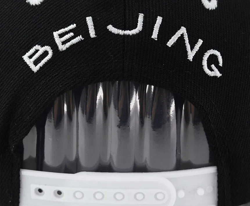 Adjustable black cotton baseball cap with embroidered lettering on the front, showing the dome crown and strap.