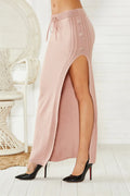 A black slim-fit midi skirt with a side-slit detail, made from acrylic fabric on a hanger.