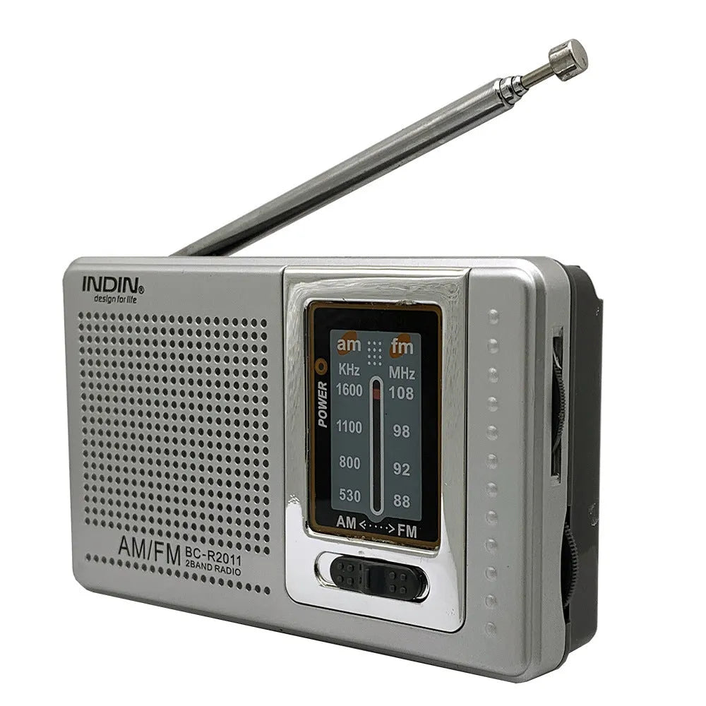 Portable silver grey FM AM radio on table, compact ABS body with built-in speaker and dial controls