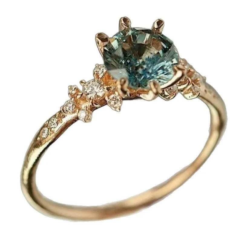 Gold coloured geometric ring with a claw setting holding a zircon stone, showing a chamfered square band.