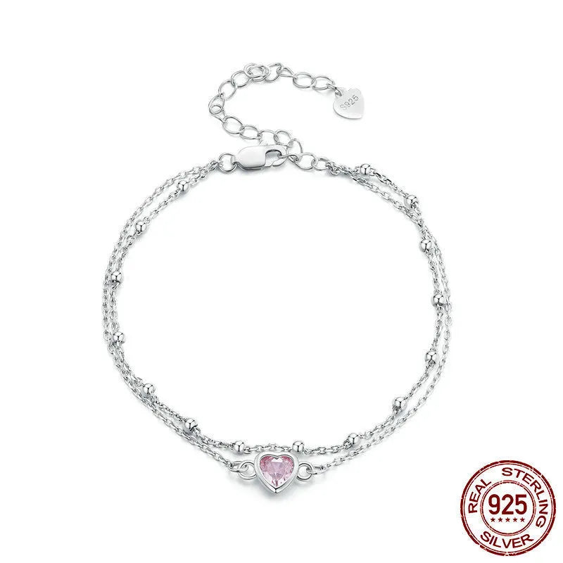 Close-up of a sweet girlish style sterling silver bracelet with a small heart pendant on an adjustable chain.