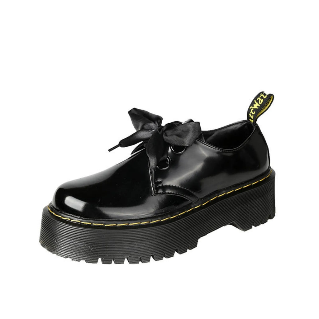 White and black women's thick soled shoes with ribbon and cross straps and laced closure.