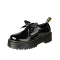 White and black women's thick soled shoes with ribbon and cross straps and laced closure.