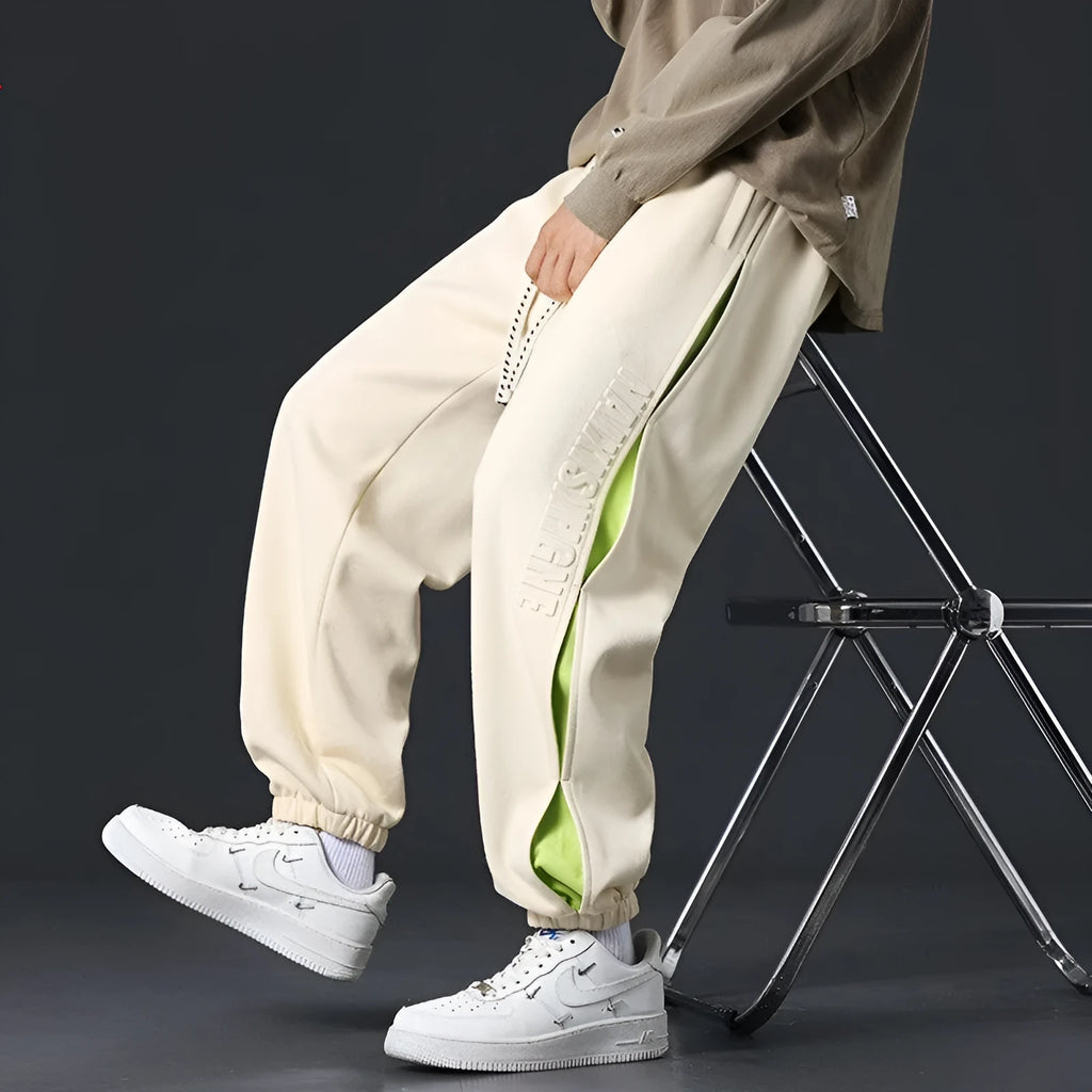 Men's loose fit cotton trousers with stitching detail and a banded ankle cuff.