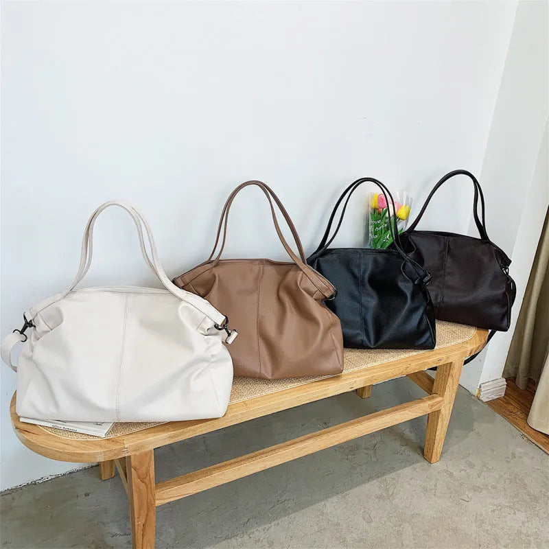 Large soft surface casual messenger bag in black showing horizontal shape and shoulder strap.