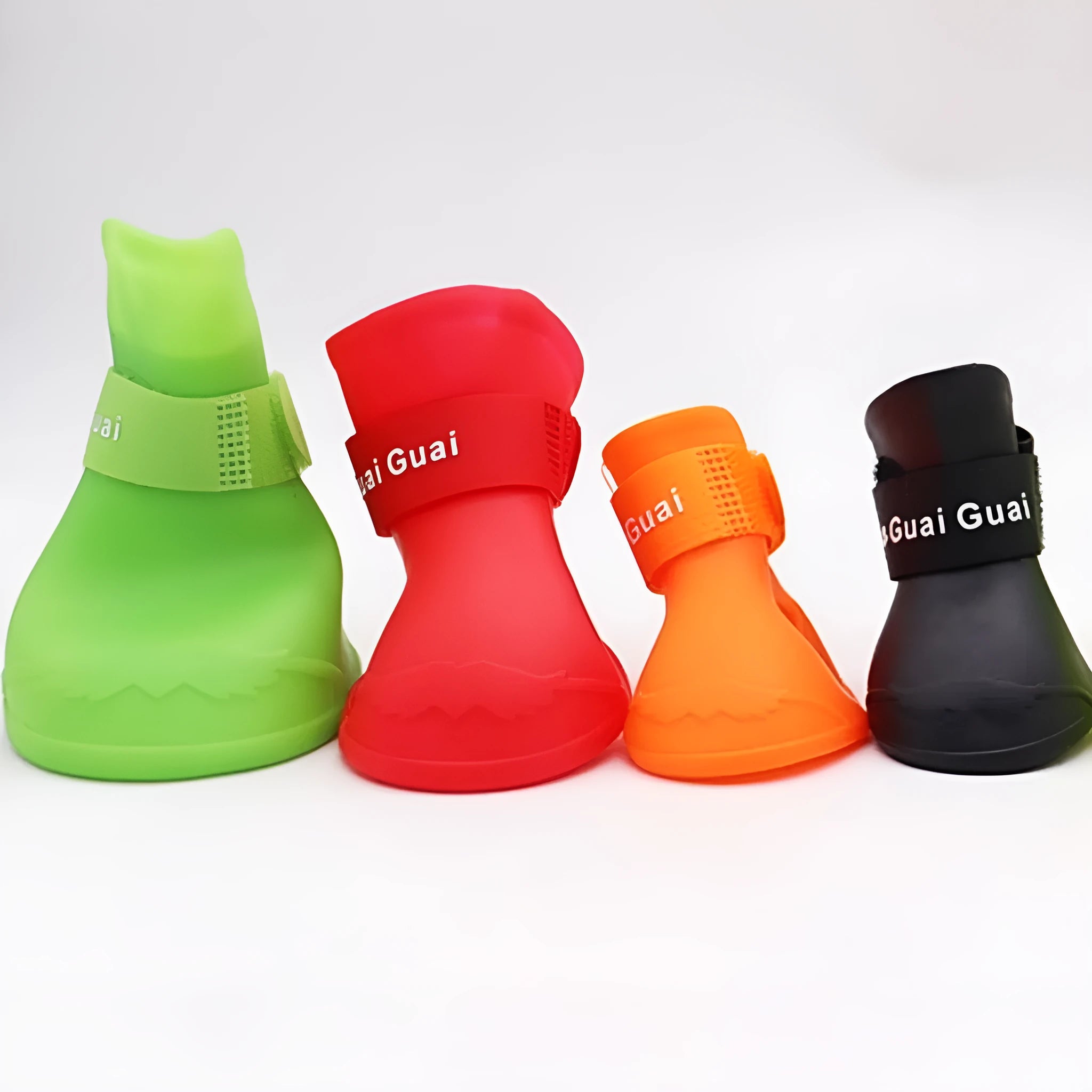 Set of four soft-soled rubber rain shoes for dogs in various colours on a wet surface.