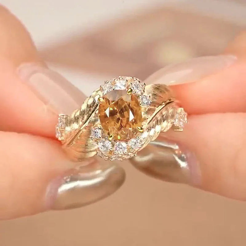 Gold-coloured embossed feather ring with geometric pattern and yellow zircon stones on a white background.