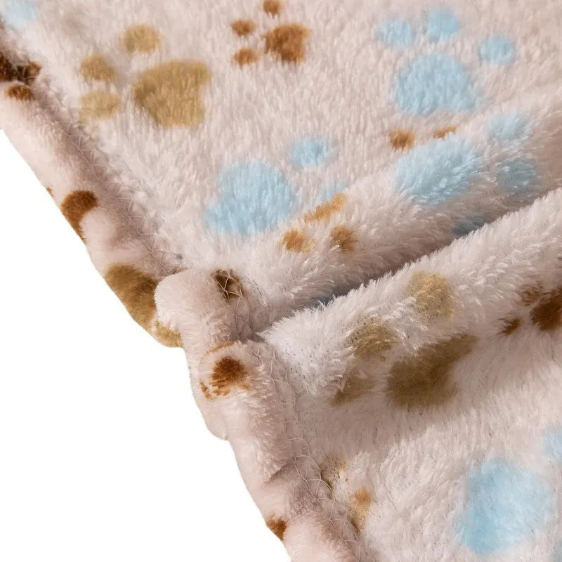 Blue cartoon dog paw print pattern on a thick double-sided flannel pet blanket laid flat.