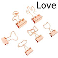 Gold metal alloy paper clip with decorative bow shape top on white background.