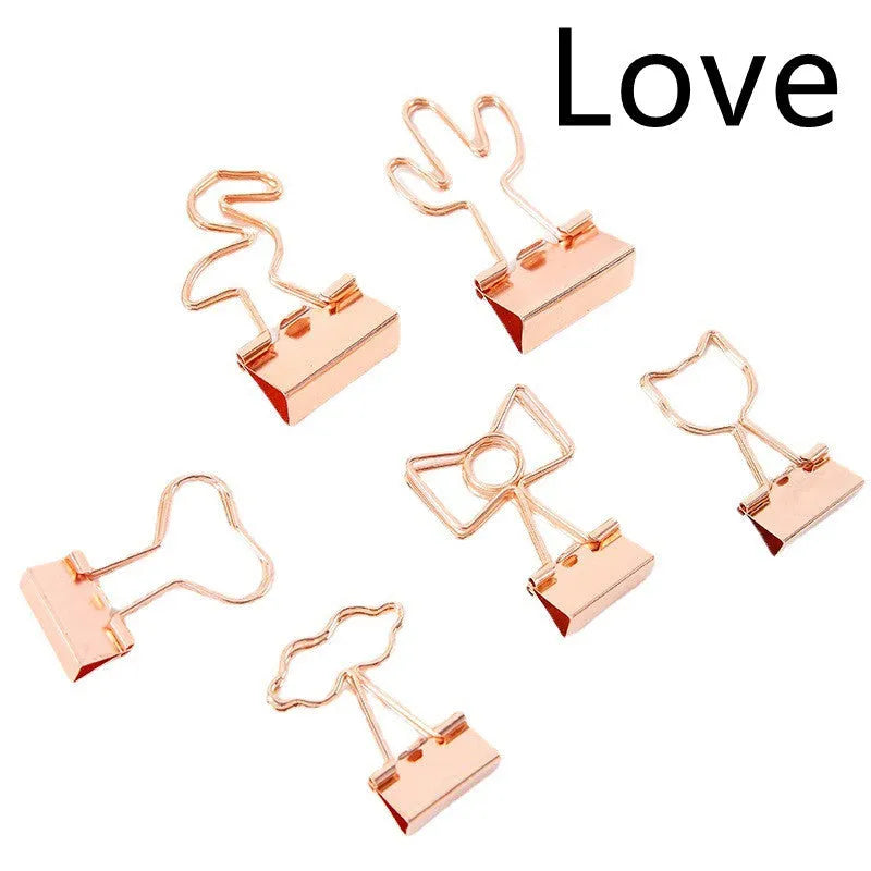 Gold metal alloy paper clip with decorative bow shape top on white background.