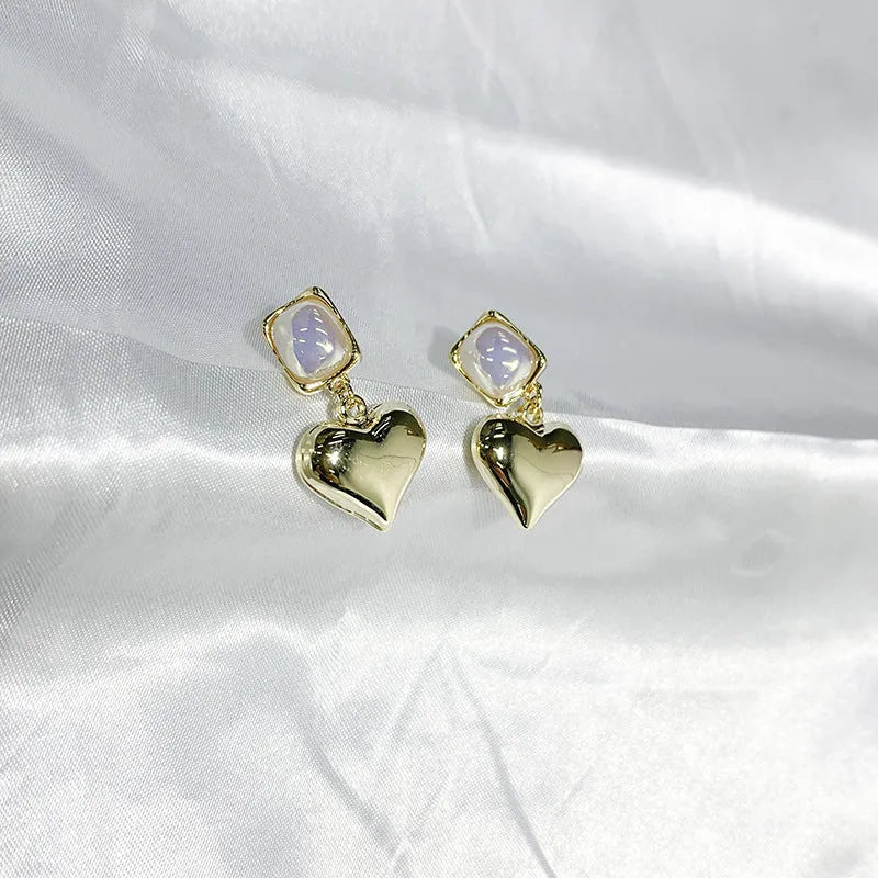 Small gold heart stud earrings with hypoallergenic metal finish on white background