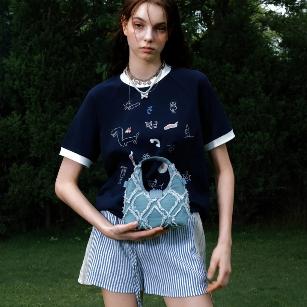 Man modelling a loose fit blue short sleeve shirt with a cartoon graphic print and contrast colour panels.